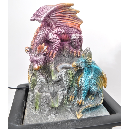 229 - A collection of four resin / plastic dragon light-up figures, comprising of a resin castle and drago... 