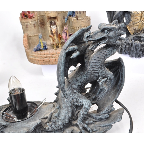 229 - A collection of four resin / plastic dragon light-up figures, comprising of a resin castle and drago... 