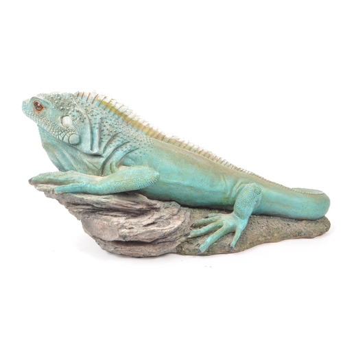 232 - A contemporary resin large Iguana figure, sitting upon a rock. Measuring approx. 22cm x 51cm.