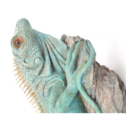 232 - A contemporary resin large Iguana figure, sitting upon a rock. Measuring approx. 22cm x 51cm.