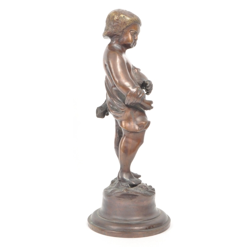 298 - A 20th century bronze sculpture of a young boy, depicted with half a robe, standing on a rock and ra... 