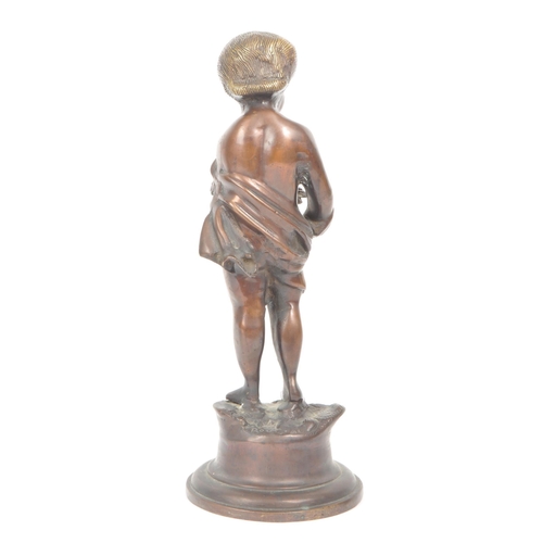 298 - A 20th century bronze sculpture of a young boy, depicted with half a robe, standing on a rock and ra... 