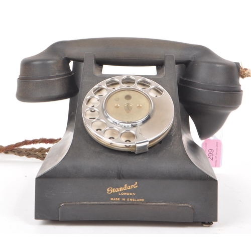 299 - Standard - An English 1958 black bakelite cased table top telephone, with a spin dial. Numbered 164-... 