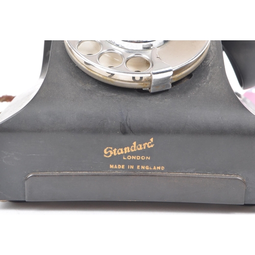 299 - Standard - An English 1958 black bakelite cased table top telephone, with a spin dial. Numbered 164-... 