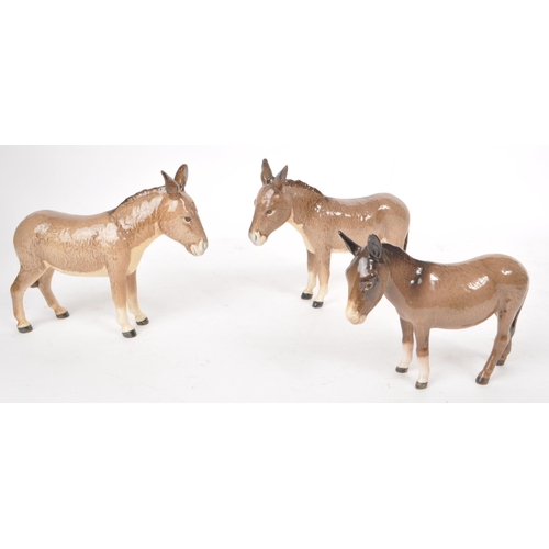 46 - Beswick - Three 20th century china donkey figurines, including two adult standing donkeys and a stan... 