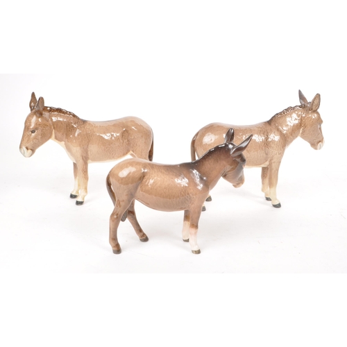 46 - Beswick - Three 20th century china donkey figurines, including two adult standing donkeys and a stan... 