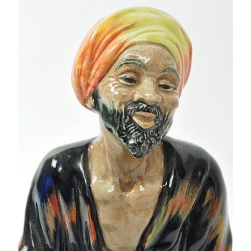 59 - Royal Doulton - A mid-century glazed porcelain sitting beggar figure no. HN 1365 'Mendicant', design... 