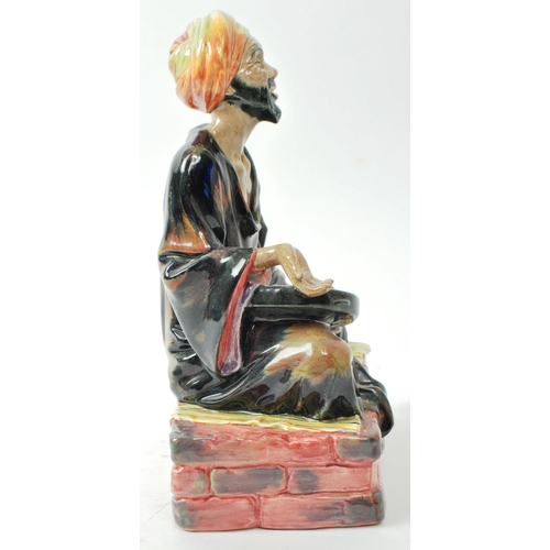 59 - Royal Doulton - A mid-century glazed porcelain sitting beggar figure no. HN 1365 'Mendicant', design... 