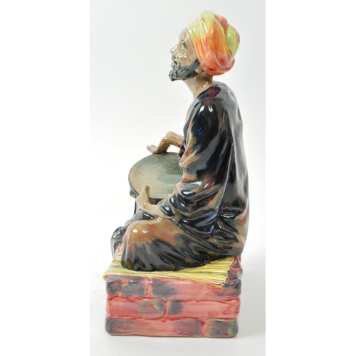 59 - Royal Doulton - A mid-century glazed porcelain sitting beggar figure no. HN 1365 'Mendicant', design... 