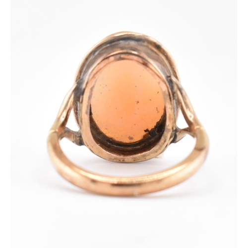 105 - A gold mounted cameo ring. The ring having a bezel set oval carved cameo to bifurcated shoulders and... 