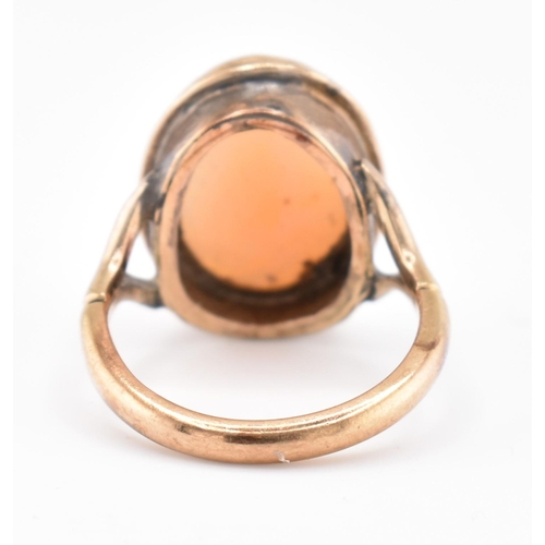 105 - A gold mounted cameo ring. The ring having a bezel set oval carved cameo to bifurcated shoulders and... 