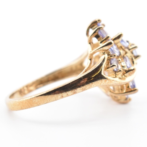 113 - A hallmarked 9ct gold and tanzanite cluster ring. The 9ct yellow gold ring having five round cut tan... 