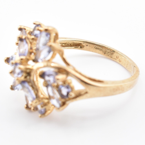 113 - A hallmarked 9ct gold and tanzanite cluster ring. The 9ct yellow gold ring having five round cut tan... 