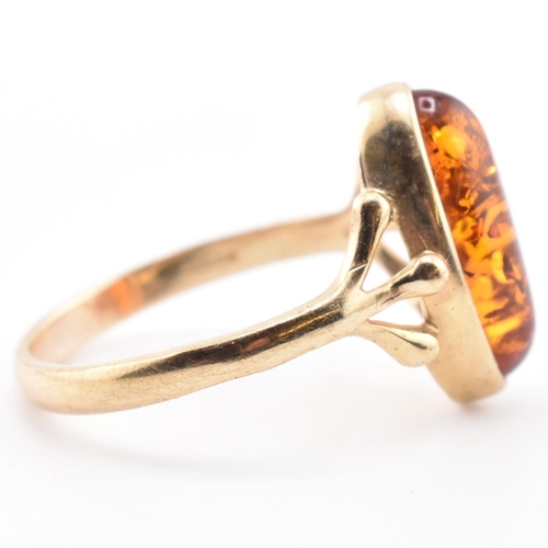 123 - A hallmarked 9ct gold and amber ring. The 9ct yellow gold ring set with a bezel set amber cabochon w... 