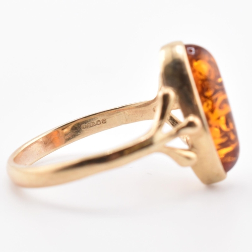 123 - A hallmarked 9ct gold and amber ring. The 9ct yellow gold ring set with a bezel set amber cabochon w... 