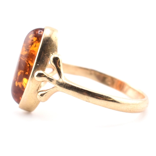 123 - A hallmarked 9ct gold and amber ring. The 9ct yellow gold ring set with a bezel set amber cabochon w... 