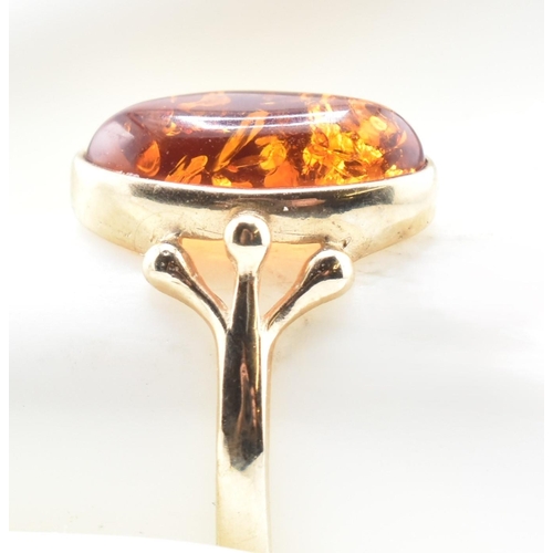 123 - A hallmarked 9ct gold and amber ring. The 9ct yellow gold ring set with a bezel set amber cabochon w... 