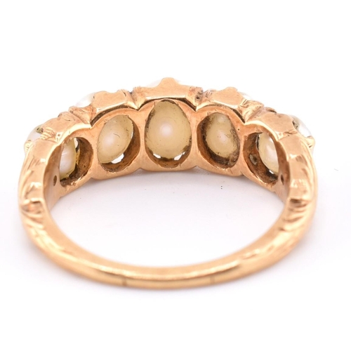 140 - A gold and pearl five stone ring. The gold ring set with five graduating full pearls to decorative s... 