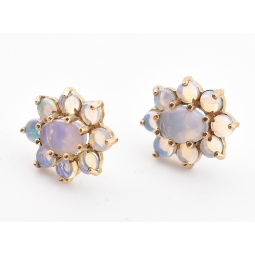 145 - A pair of 9ct gold and opal cluster stud earrings. The 9ct yellow gold earrings having a central cla... 