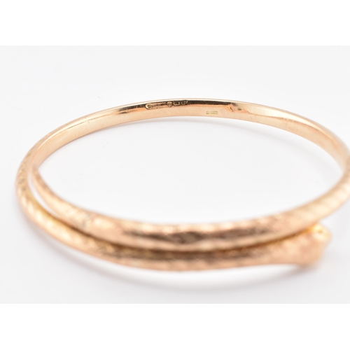 17 - A 19th-century hallmarked 9ct gold snake bangle. The bangle with textured and etched body. Hallmarke... 