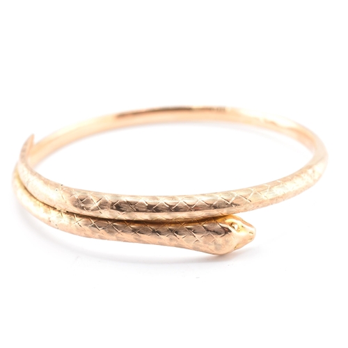 17 - A 19th-century hallmarked 9ct gold snake bangle. The bangle with textured and etched body. Hallmarke... 