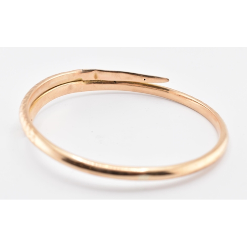 17 - A 19th-century hallmarked 9ct gold snake bangle. The bangle with textured and etched body. Hallmarke... 