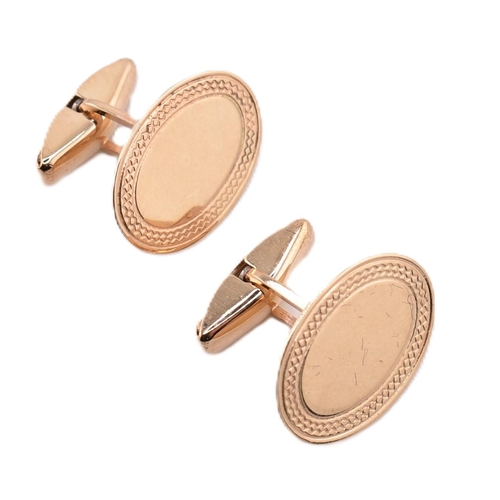 180 - A pair of hallmarked 9ct gold cufflinks. The cufflinks having oval faces framed by engined turned de... 