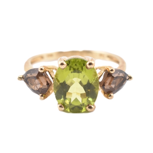 197 - A hallmarked 9ct gold changbai peridot and smoky quartz ring. The 9ct yellow gold ring set with a ce... 