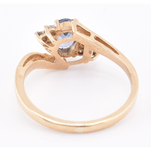 206 - A hallmarked 9ct gold sapphire and diamond crossover ring. The 9ct yellow gold ring set with a centr... 