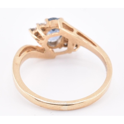 206 - A hallmarked 9ct gold sapphire and diamond crossover ring. The 9ct yellow gold ring set with a centr... 