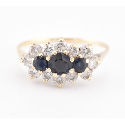 214 - A hallmarked 18ct gold sapphire and white stone cluster ring. The 18ct yellow gold ring set with thr... 