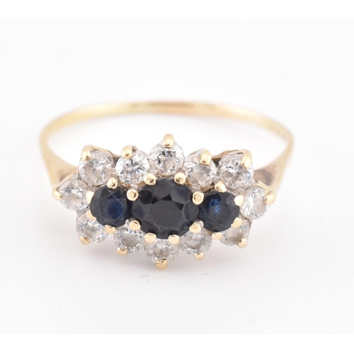 214 - A hallmarked 18ct gold sapphire and white stone cluster ring. The 18ct yellow gold ring set with thr... 