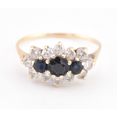 214 - A hallmarked 18ct gold sapphire and white stone cluster ring. The 18ct yellow gold ring set with thr... 