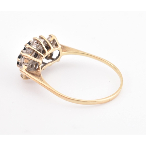 214 - A hallmarked 18ct gold sapphire and white stone cluster ring. The 18ct yellow gold ring set with thr... 