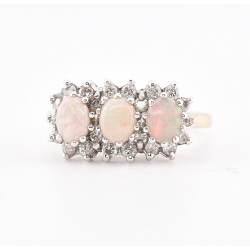 218 - A hallmarked 9ct gold opal and diamond three stone ring. The yellow gold ring set with three claw se... 