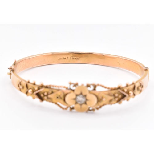 23 - An early 20th century hallmarked 9ct gold and diamond hinged bangle. The bangle set with a central o... 