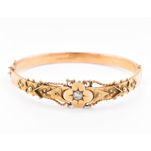 23 - An early 20th century hallmarked 9ct gold and diamond hinged bangle. The bangle set with a central o... 