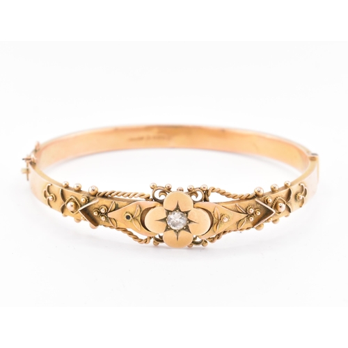 23 - An early 20th century hallmarked 9ct gold and diamond hinged bangle. The bangle set with a central o... 