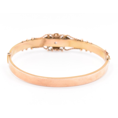 23 - An early 20th century hallmarked 9ct gold and diamond hinged bangle. The bangle set with a central o... 