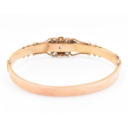 23 - An early 20th century hallmarked 9ct gold and diamond hinged bangle. The bangle set with a central o... 