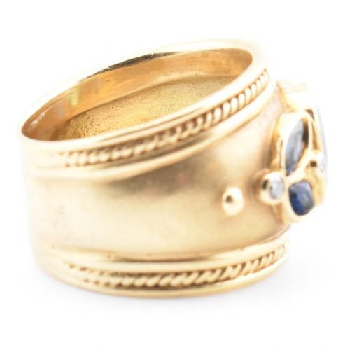 28a - An Etruscan style hallmarked 18ct gold, tourmaline, sapphire and diamond ring. The 18ct gold band ri... 