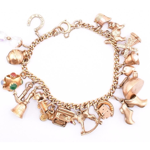 29 - A 9ct gold charm bracelet. The 9ct yellow gold curb link chain bracelet strung with twenty 9ct gold ... 