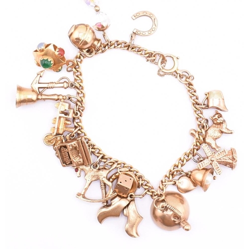 29 - A 9ct gold charm bracelet. The 9ct yellow gold curb link chain bracelet strung with twenty 9ct gold ... 