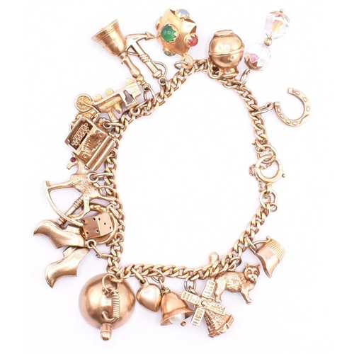 29 - A 9ct gold charm bracelet. The 9ct yellow gold curb link chain bracelet strung with twenty 9ct gold ... 