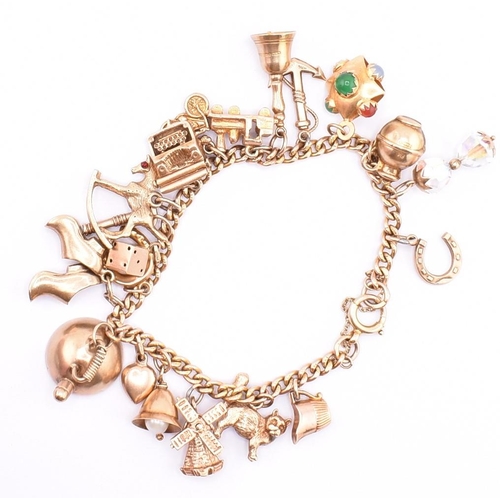 29 - A 9ct gold charm bracelet. The 9ct yellow gold curb link chain bracelet strung with twenty 9ct gold ... 