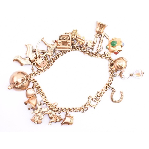 29 - A 9ct gold charm bracelet. The 9ct yellow gold curb link chain bracelet strung with twenty 9ct gold ... 