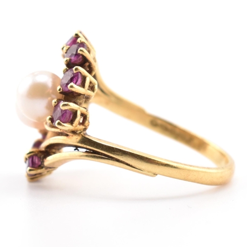 31 - A hallmarked 18ct gold ruby and pearl crossover ring. The 18ct yellow gold ring set with two round p... 