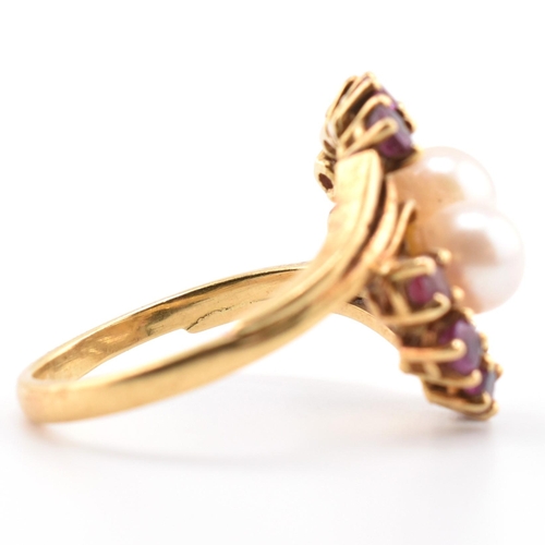 31 - A hallmarked 18ct gold ruby and pearl crossover ring. The 18ct yellow gold ring set with two round p... 