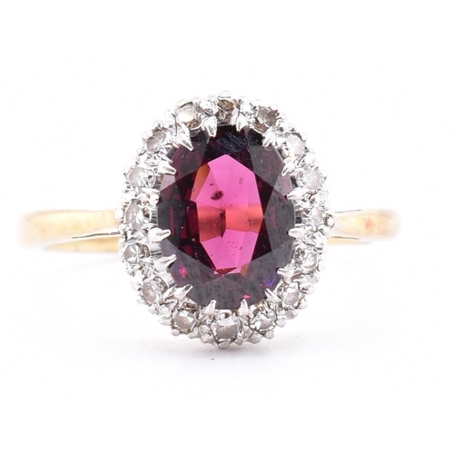 31A - An 18ct gold and platinum garnet and diamond cluster ring. The 18ct yellow gold ring set with a claw... 