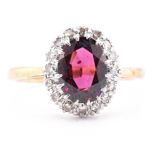 31A - An 18ct gold and platinum garnet and diamond cluster ring. The 18ct yellow gold ring set with a claw... 